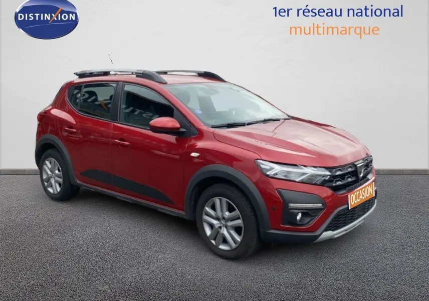 Vue 3/4 avant gauche d'une Dacia Sandero Stepway rouge fusion métal avec protections noires et barres de toit.