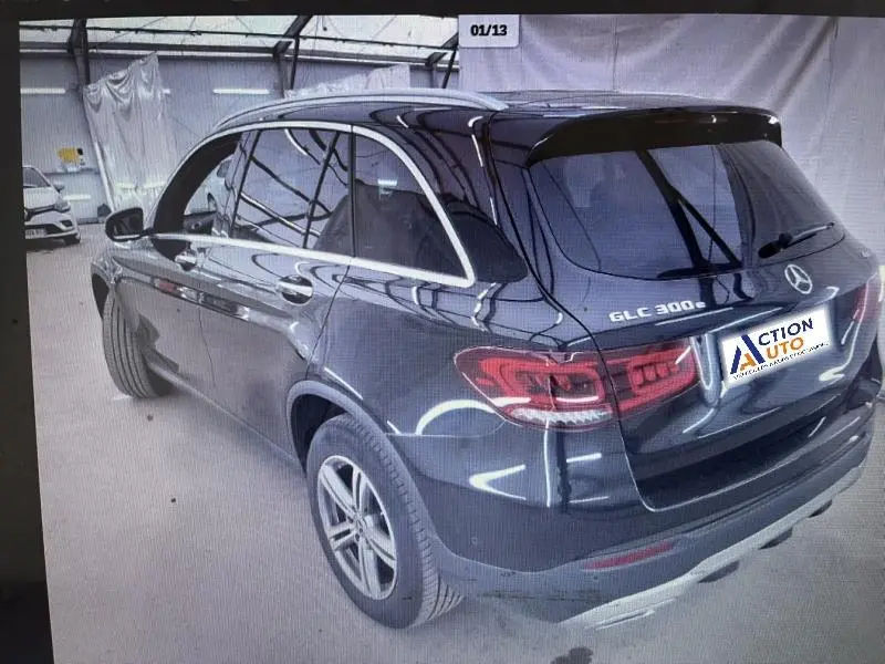 Vue 3/4 arrière droite d’un Mercedes GLC 300 e noir avec vitres surteintées et jantes alliage en intérieur d’atelier.