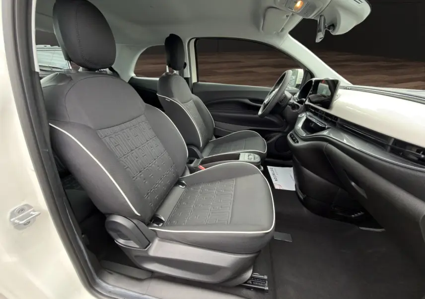 Vue intérieure côté conducteur de la Fiat 500 blanche 2023, sièges noirs avec surpiqûres claires et tableau de bord épuré.