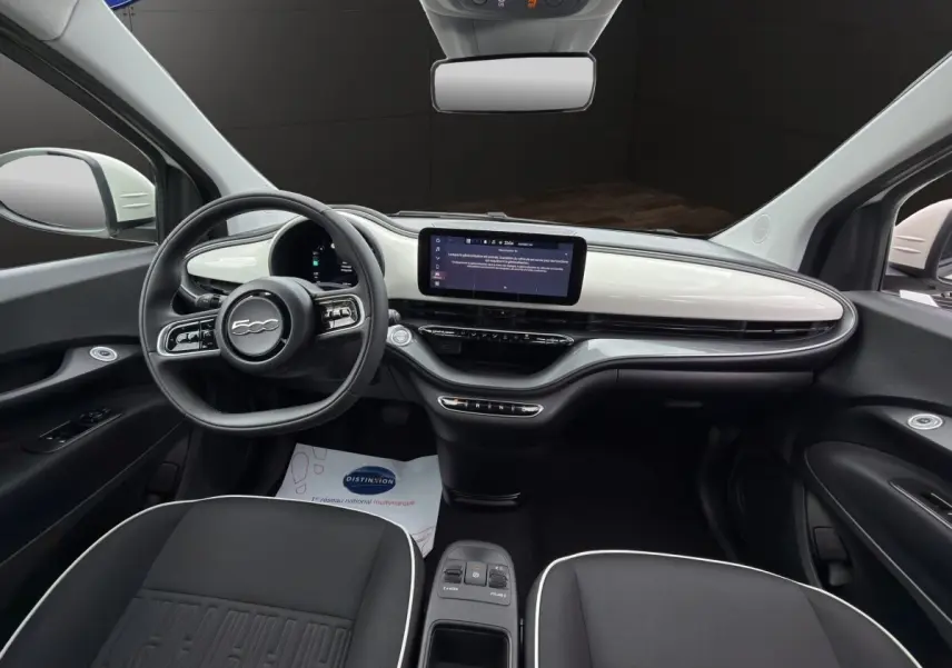 Intérieur avant de la FIAT 500 blanc, vue centrée sur le tableau de bord avec écran tactile et volant multifonctions.
