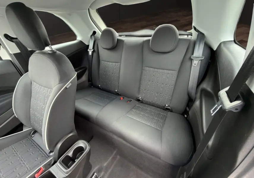 Vue intérieure arrière côté droit de la FIAT 500 blanche, sièges noirs avec motif FIAT embossé.