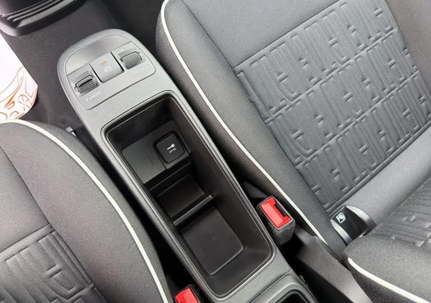 Vue rapprochée de la console centrale et des sièges gris foncé avec surpiqûres blanches d'une Fiat 500 électrique blanche.
