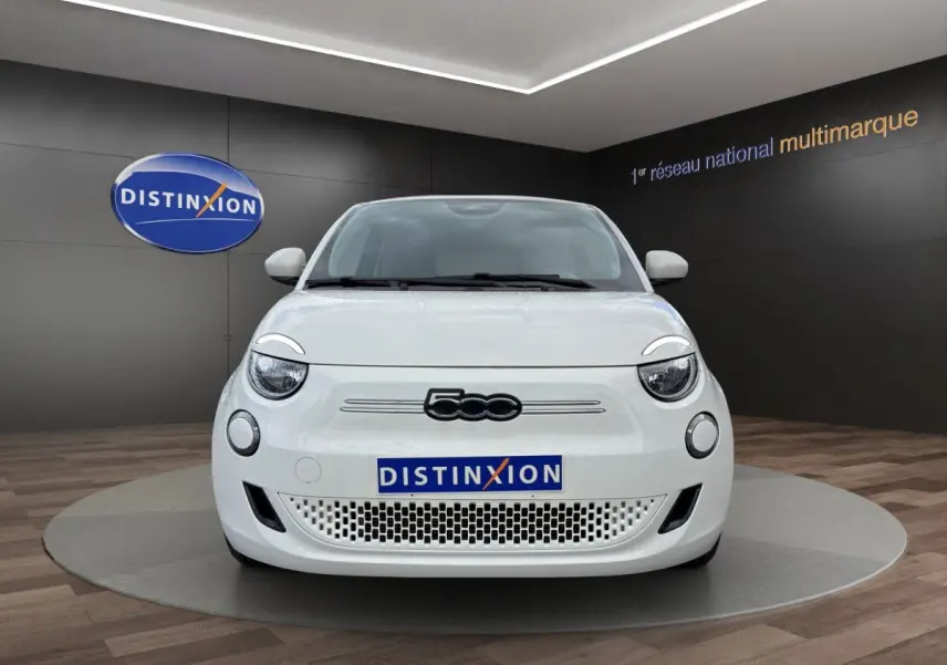 Vue frontale d'une FIAT 500 électrique blanche 2023 avec logo 500 noir et plaque Distinxion en showroom.