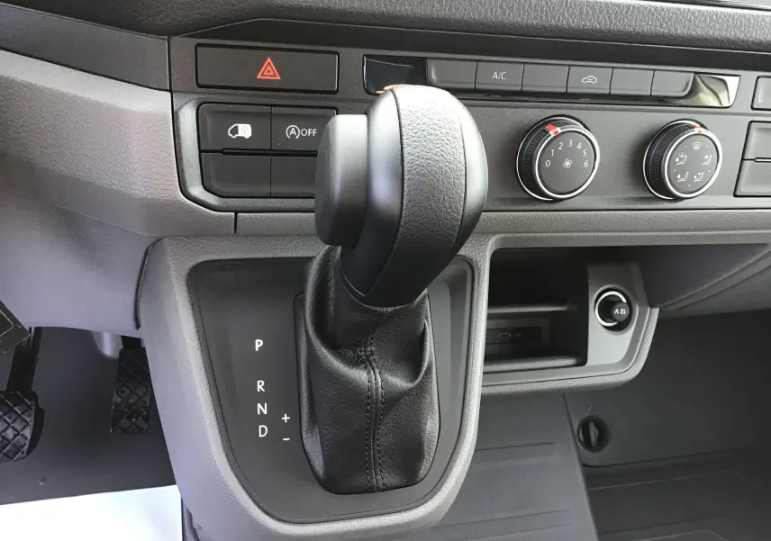 Le levier de vitesses automatique noir du Volkswagen Crafter Fourgon 2024, avec commandes de climatisation et tableau de bord gris.