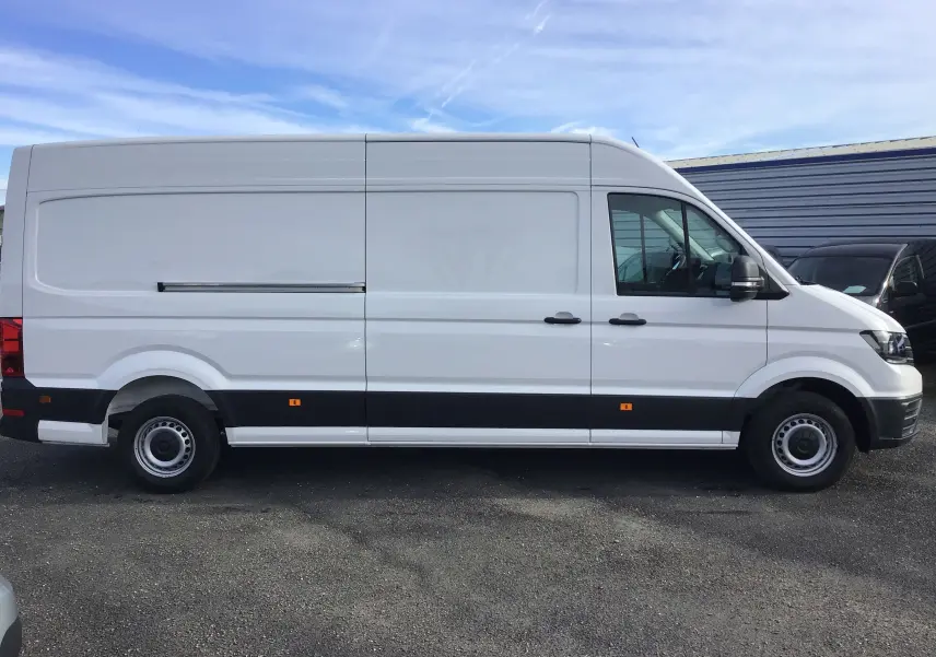 Vue latérale droite d'un utilitaire Volkswagen Crafter blanc, version L4H3 2024 avec bande noire basse et jantes acier simples.