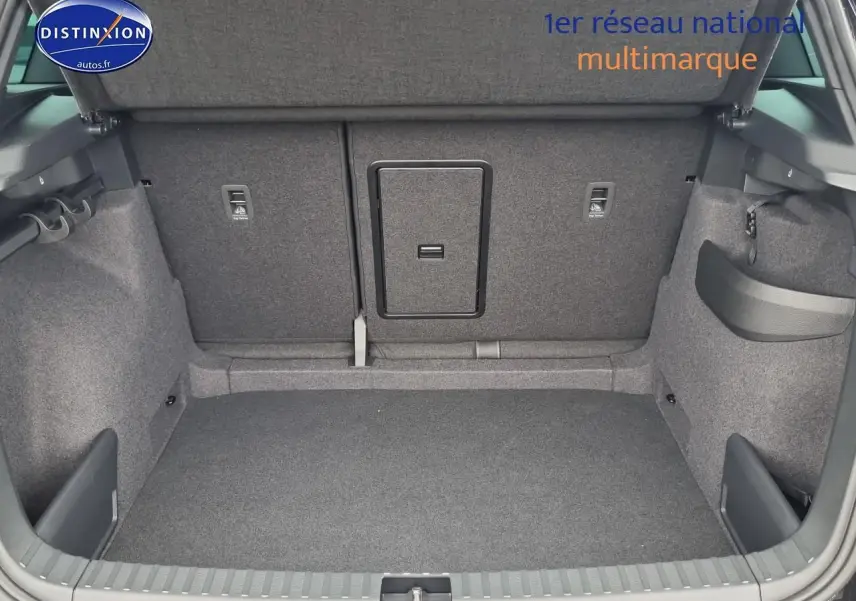 Coffre ouvert d’un Skoda Karoq noir 2025, montrant la banquette arrière avec trappe à skis centrale.