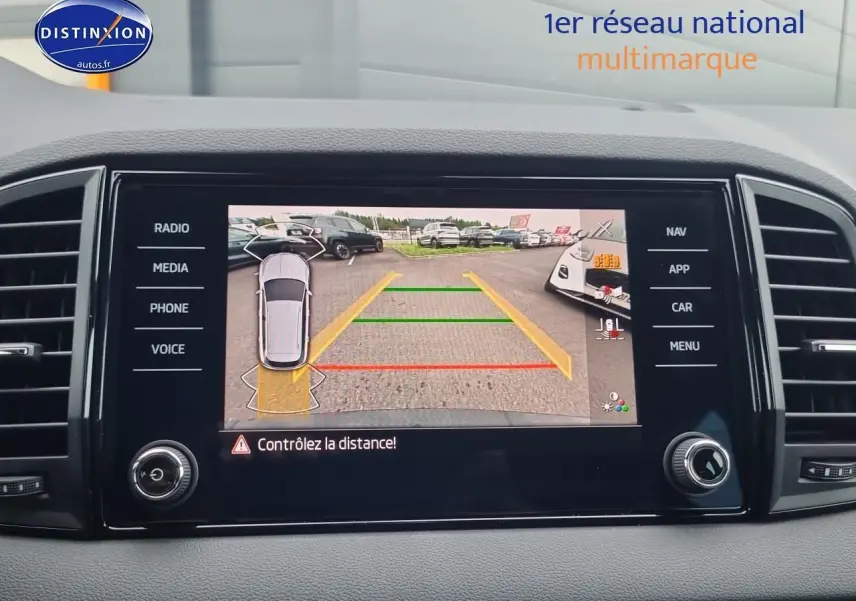 Écran tactile intérieur montrant la caméra de recul du Skoda Karoq noir, avec lignes d’aide au stationnement colorées.