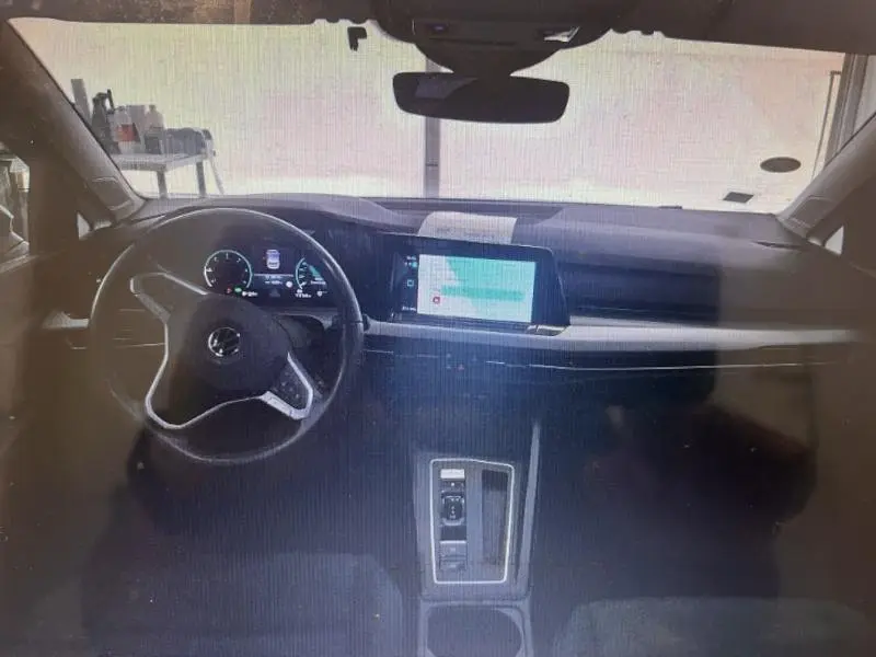 Vue intérieure avant de la Volkswagen Golf 2.0 TDI noire, avec tableau de bord numérique et écran tactile central lumineux.