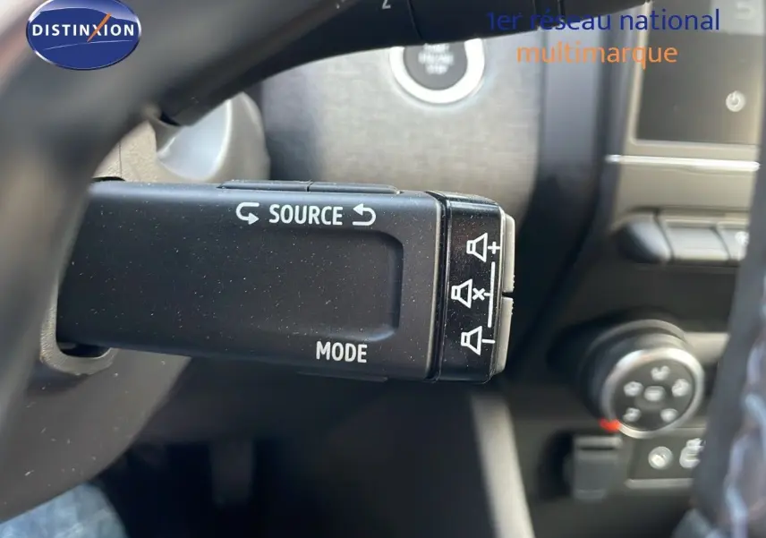 Gros plan sur la commande au volant de la Renault Clio gris schiste, avec boutons source et mode visibles.