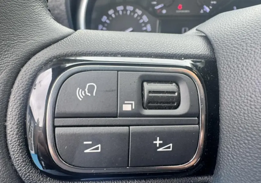 Gros plan sur les commandes vocales et volume au volant cuir du Citroën C3 Aircross 2024 gris acier.