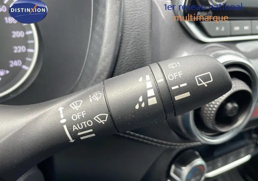 Gros plan sur la commande d'essuie-glace du Nissan Juke Hybrid 2023, avec tableau de bord et aérateurs visibles.