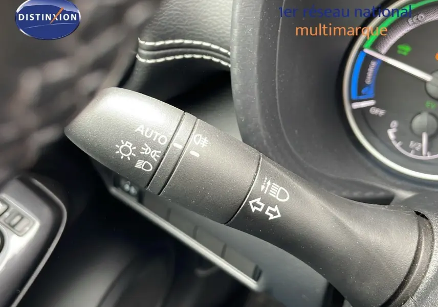 Gros plan sur la commande des feux et clignotants du Nissan Juke Hybrid 2023 avec tableau de bord partiellement visible.