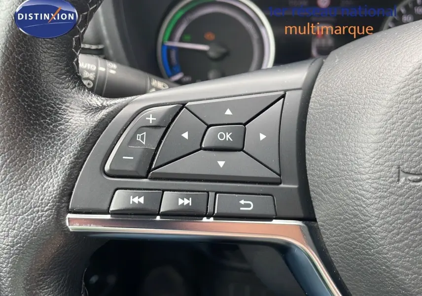Gros plan sur les commandes au volant du Nissan Juke Hybrid 2023, avec cuir noir et tableau de bord partiellement visible.