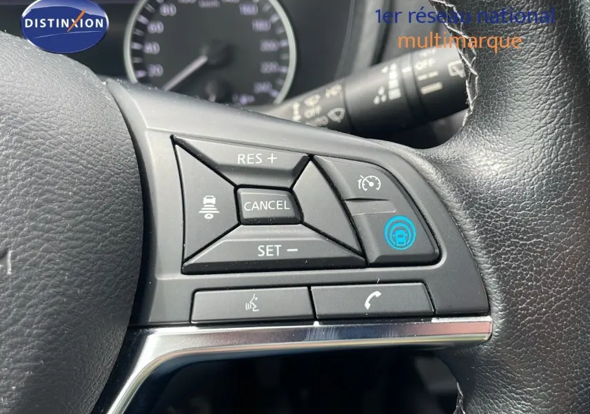 Gros plan sur les commandes au volant en cuir noir du Nissan Juke Hybrid 2023, avec boutons de régulateur de vitesse et appel.