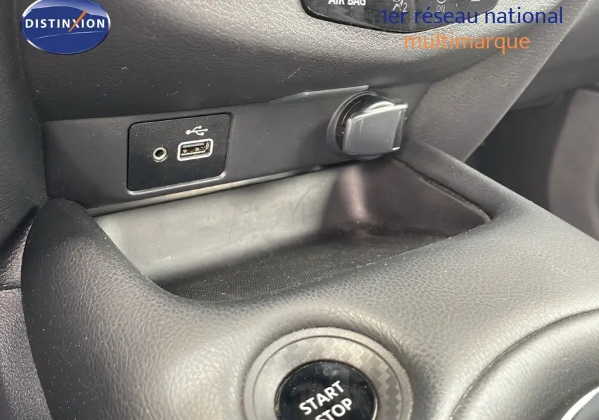 Gros plan sur la console centrale du Nissan Juke Hybrid 2023, montrant le bouton Start Stop et les ports USB et allume-cigare.
