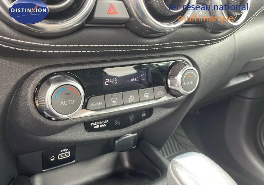 Détail de la console centrale du Nissan Juke Hybrid 2023 avec commandes climatisation et port USB, finition cuir gris.