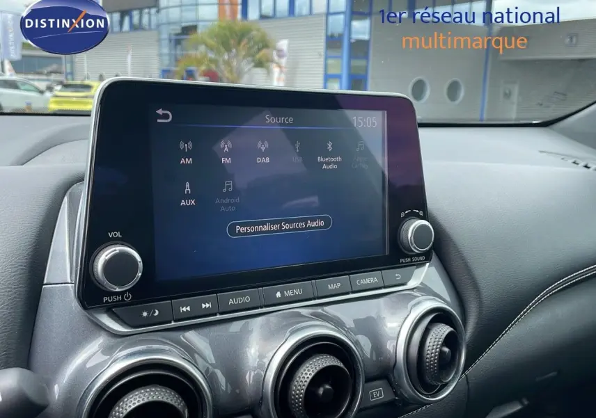 Écran tactile central et commandes de climatisation du Nissan Juke Hybrid 143ch Business 2023 en gris perle métal.