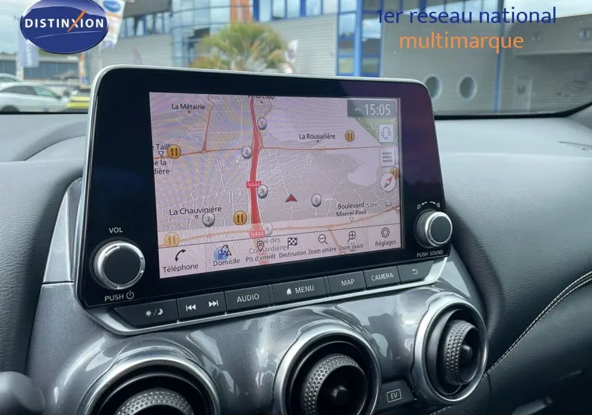 Vue rapprochée de l'écran tactile central et des aérateurs gris perle métallisé du tableau de bord du Nissan Juke Hybrid 2023.