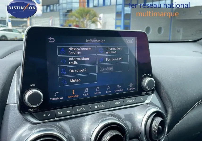 Écran tactile central du Nissan Juke Hybrid 2023 affichant menu d'informations, entouré de commandes et aérateurs gris perle métallisé.