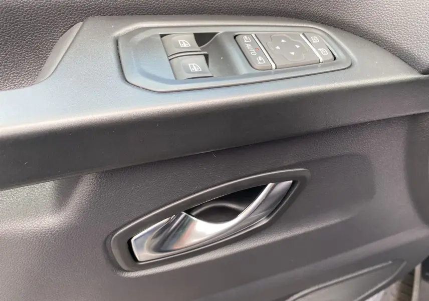 Poignée de porte intérieure grise avec commandes électriques des vitres et rétroviseurs du Renault Trafic cabine approfondie.