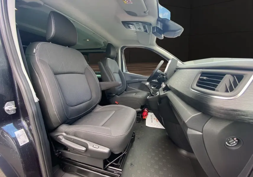 Intérieur avant du Renault Trafic gris comète, sièges noirs avec accoudoirs et tableau de bord moderne vu côté conducteur.