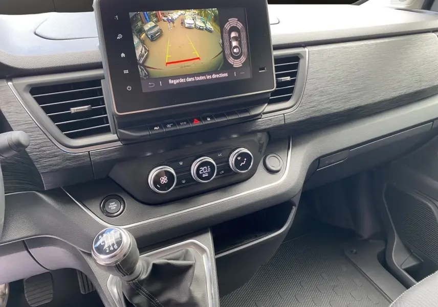 Vue intérieure du tableau de bord du Renault Trafic gris comète avec écran tactile et levier de vitesses manuel.