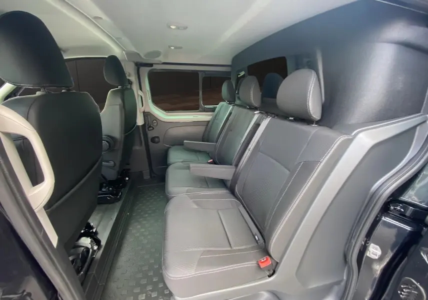 Vue intérieure côté droit des sièges arrière noirs du Renault Trafic Cabine Approfondie 2025 avec porte latérale ouverte.