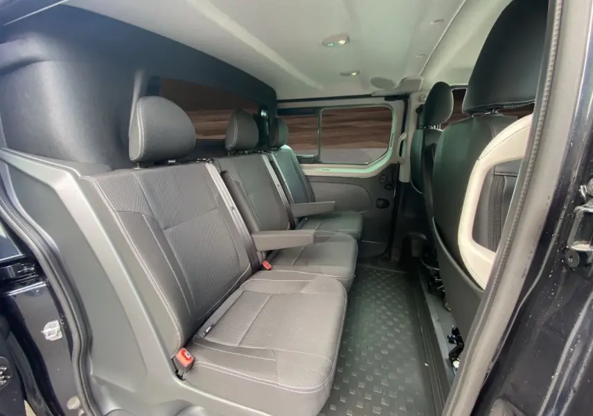 Vue intérieure côté droit des sièges arrière noirs du Renault Trafic Cabine Approfondie 2025 avec porte latérale ouverte.