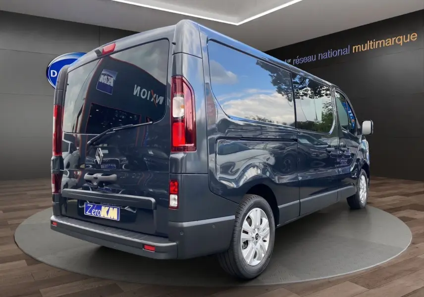 Vue 3/4 arrière droit d’un Renault Trafic cabine approfondie gris comète avec hayon vitré et jantes alu 17 pouces.