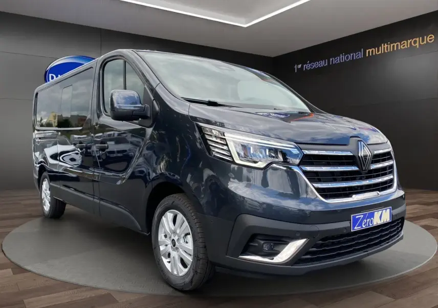 Renault Trafic cabine approfondie gris comète vu en 3/4 avant droit avec calandre chromée et phares LED allumés.