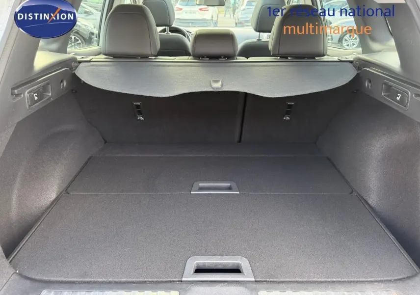 Vue intérieure du coffre spacieux d'un Renault Kadjar blanc nacré, avec banquette arrière et cache-bagages déployés.