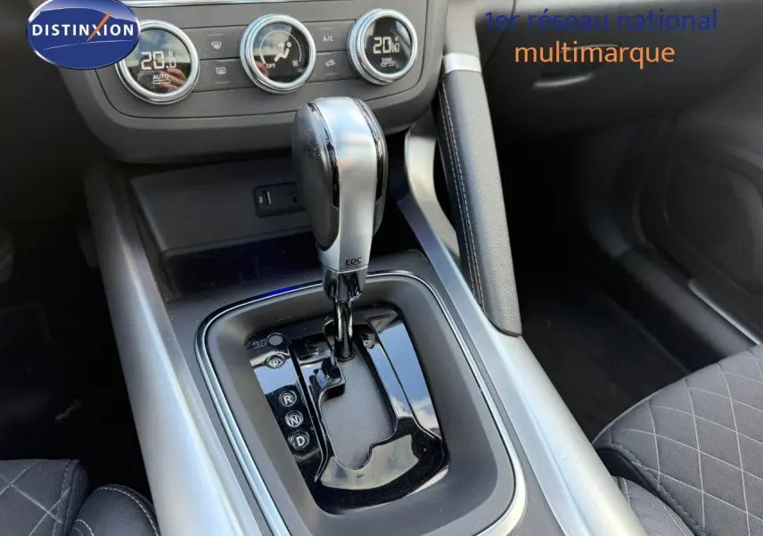 Gros plan sur la console centrale du Renault Kadjar blanc nacré, mettant en valeur le levier de vitesse automatique et les commandes de climatisation.