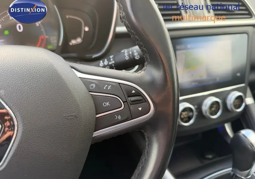 Gros plan sur le volant en cuir noir et la console centrale avec écran tactile du Renault Kadjar blanc nacré 2019.