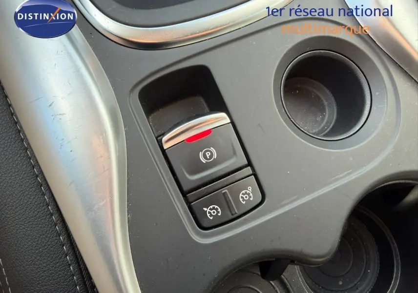 Gros plan sur la console centrale du Renault Kadjar blanc nacré, montrant le frein à main électronique et commandes de régulateur.