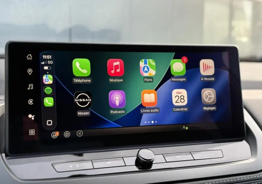 Écran tactile intérieur du Nissan Qashqai blanc nacré, affichant Apple CarPlay avec icônes colorées.