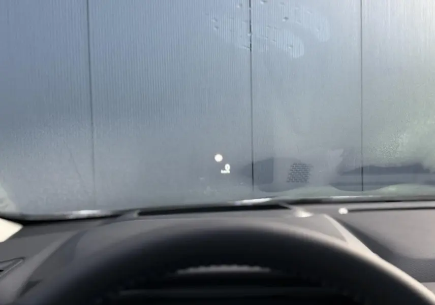 Vue intérieure du tableau de bord du Nissan Qashqai blanc nacré 2025 avec affichage tête haute sur pare-brise.