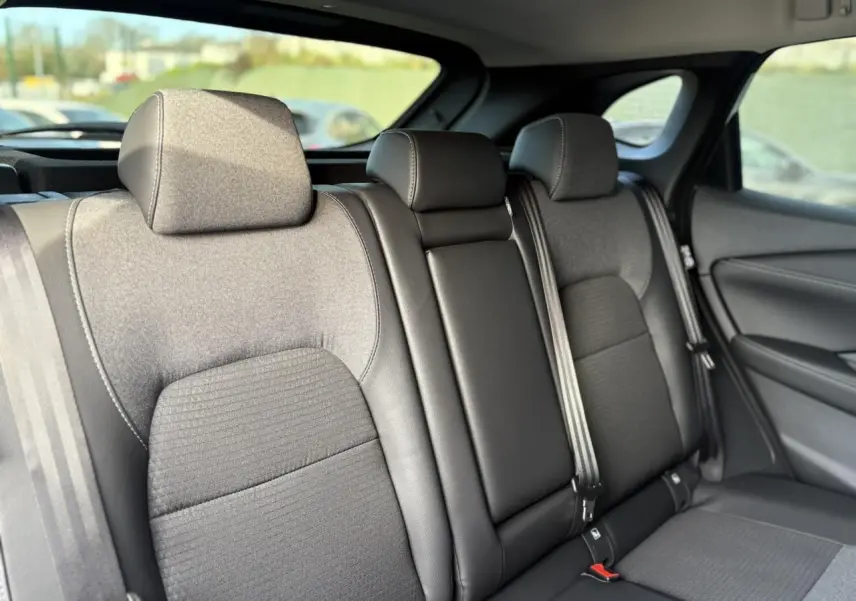 Vue intérieure des sièges arrière gris foncé du Nissan Qashqai III blanc nacré, avec appuie-têtes et ceintures visibles.