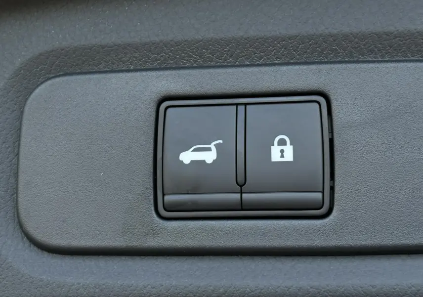 Boutons d'ouverture électrique du hayon et de verrouillage sur panneau intérieur du Nissan Qashqai blanc nacré.