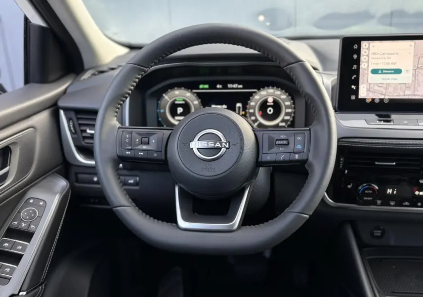 Vue frontale du volant cuir noir du Nissan Qashqai 2025 avec tableau de bord numérique et écran tactile central.