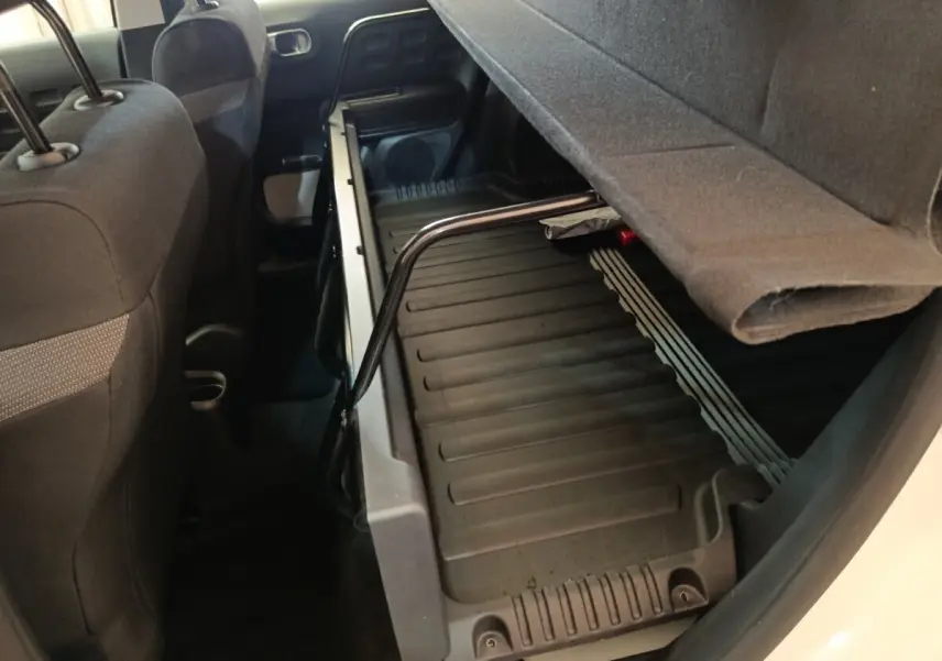 Vue intérieure arrière côté droit du coffre modulable de la Citroën C3 blanche avec banquette relevée.