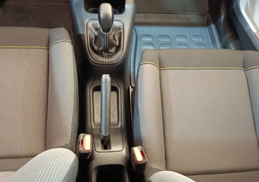 Vue intérieure centrée sur la console centrale et la boîte manuelle de la Citroën C3, sièges gris avec surpiqûres jaunes.