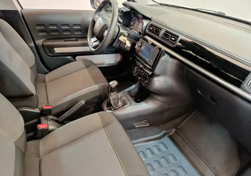 Vue intérieure côté conducteur de la Citroën C3 2021 avec tableau de bord noir et sièges tissu gris.