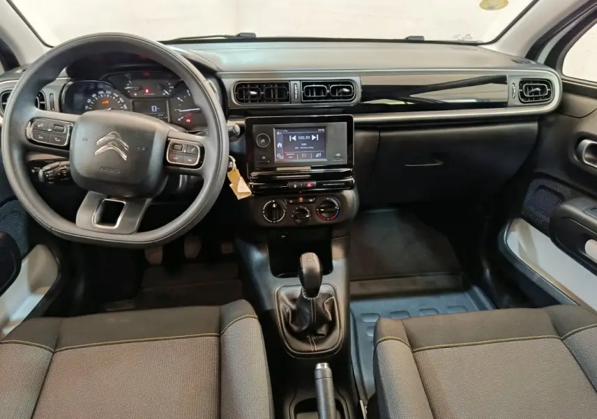 Vue intérieure avant de la Citroën C3 blanche 2021, volant multifonctions, tableau de bord noir avec écran tactile central.
