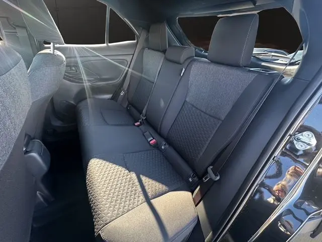 Vue intérieure du siège arrière côté droit du Toyota Yaris Cross 130H Design noir 2025 avec sellerie tissu et ceintures de sécurité.