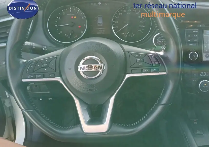 Vue rapprochée du volant noir du Nissan Qashqai blanc 2018 avec tableau de bord et commandes visibles.