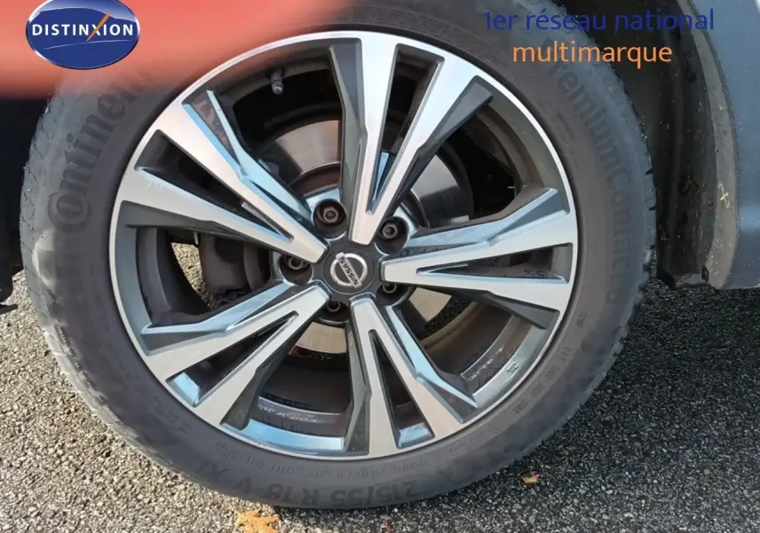 Gros plan sur la roue avant droite du Nissan Qashqai blanc de 2018 avec jante alliage bicolore distinctive.