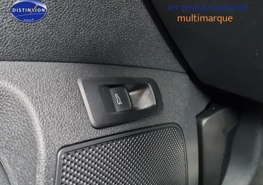 Gros plan sur le bouton d'ouverture du coffre et la grille du haut-parleur dans l'habitacle noir du Skoda Karoq 2025.