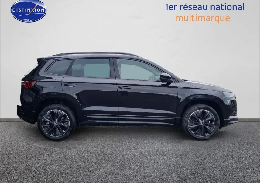 Vue de profil côté gauche d'un Skoda Karoq noir 2025 avec jantes alu et barres de toit.