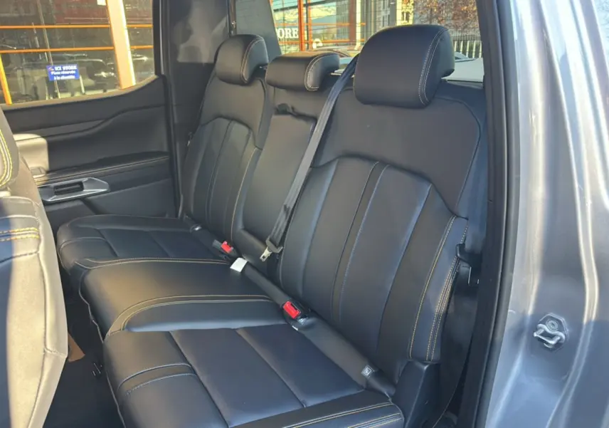 Vue intérieure sur la banquette arrière en cuir noir avec surpiqûres jaunes du Ford Ranger 2025 gris iconic, porte ouverte côté droit.