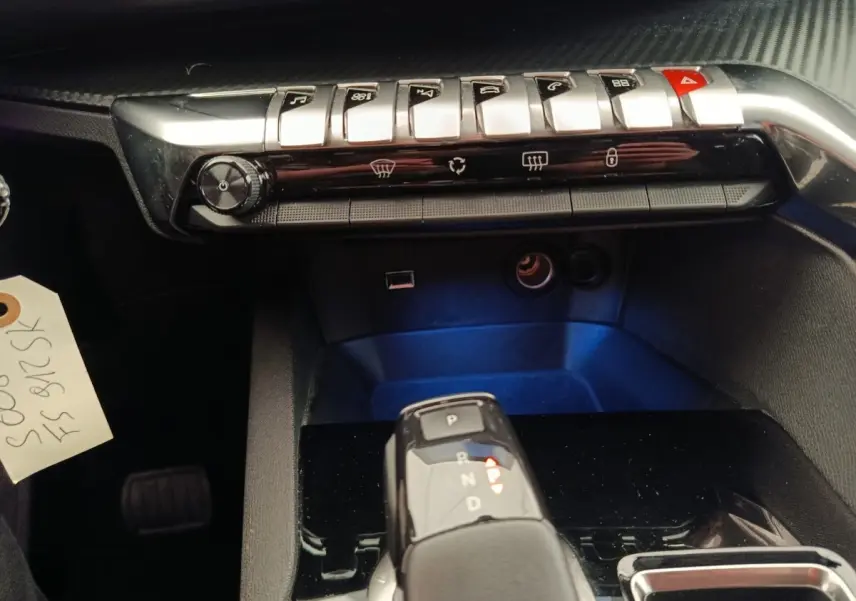 Gros plan sur la console centrale du Peugeot 5008 gris foncé, avec levier de vitesse automatique et commandes piano.